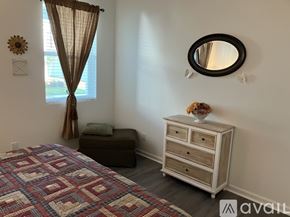Hardeeville house for rent - A bedroom with a bed, a dresser, and a window with curtains.