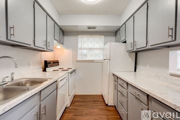 Hattiesburg apartment for rent - A kitchen with white cabinets and a white fridge.