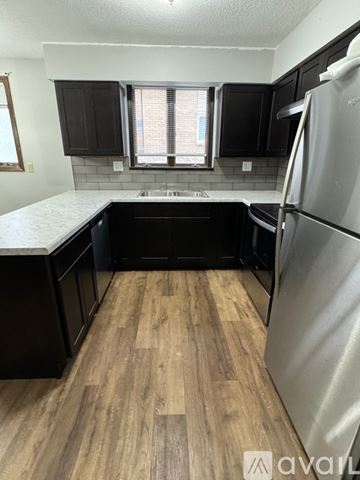 Mankato apartment for rent - A kitchen with black cabinets and a wooden floor.