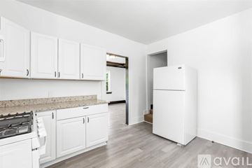 Detroit house for rent - A kitchen with white cabinets and a white fridge.