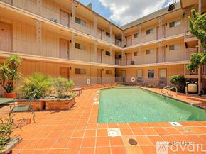 Austin apartment for rent - A large outdoor pool surrounded by a patio and balconies of a residential building.