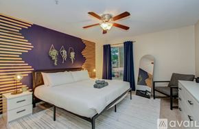 Houston apartment for rent - A bedroom with a bed, a ceiling fan, and a wall decoration.