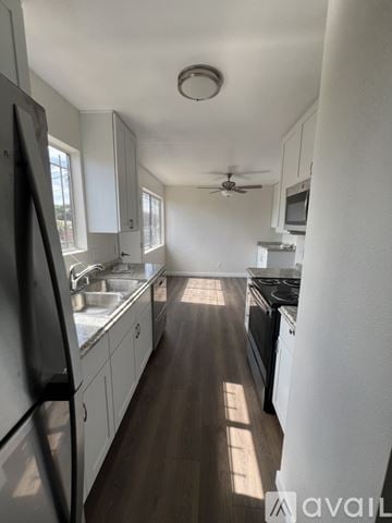 National City house for rent - A kitchen with white cabinets and a black fridge.