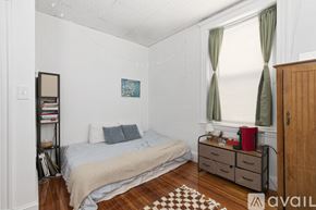 Cambridge apartment for rent - A bedroom with a bed, nightstand, and a window with green curtains.
