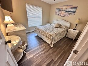Bradenton condo for rent - A bedroom with a bed, chair, and lamp.