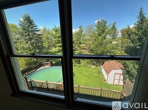 State College house for rent - A view from a window looking out at a pool and a house.