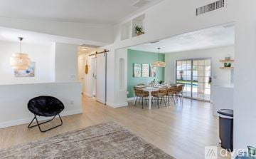 Lake Havasu City house for rent - A living room with a black chair and a dining table with chairs.