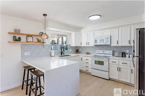 Lake Havasu City house for rent - A kitchen with white cabinets and a white island with bar stools.