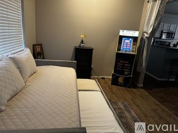 Lake Havasu City house for rent - A living room with a couch, a small table with a flower vase, and a cabinet with a video game console.