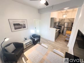 San Diego apartment for rent - A living room with a black couch, a grey rug, and a framed picture on the wall.