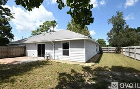 Lecanto townhouse for rent - A white house with a grey roof is surrounded by a fence and trees.