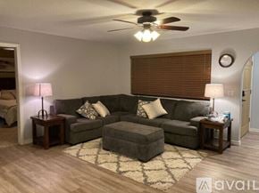 Lake Havasu City house for rent - A living room with a grey couch, a rug, and a ceiling fan.