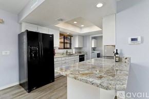 Lake Havasu City house for rent - A black refrigerator is in a kitchen with granite countertops.