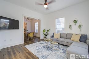 Houston house for rent - A living room with a grey couch, a yellow chair, a blue rug, and a ceiling fan.