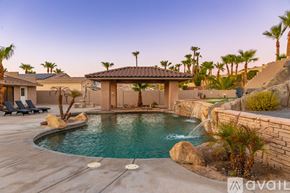 Lake Havasu City house for rent - A pool with a waterfall and a gazebo in the middle of it.