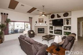 Lake Havasu City house for rent - A living room with a brown couch, a fireplace, and a TV mounted on the wall.