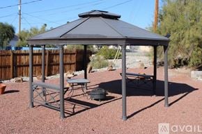 Lake Havasu City house for rent - A gazebo with a table and chairs is set up in a backyard.