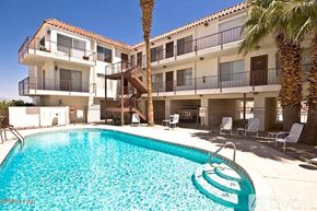 Lake Havasu City apartment for rent - A large swimming pool is in front of a white building with a balcony.