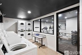 Chicago apartment for rent - A modern laundry room with a washer and dryer, a folding table, and a view into the living room.