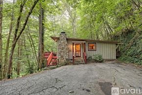 Lakemont house for rent - A small house with a stone chimney is surrounded by trees.