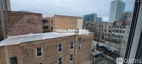 Chicago apartment for rent - A view of a cityscape from a window with a building in the foreground and a street below.