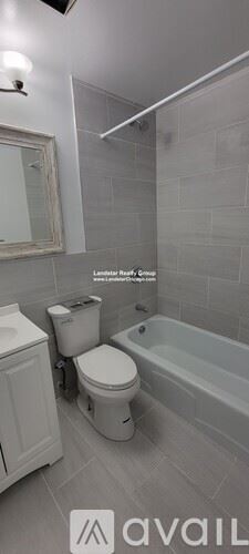Chicago apartment for rent - A bathroom with a toilet, a bathtub, and a mirror.