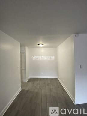 Chicago apartment for rent - A room with a wooden floor and white walls, with a logo and text for Landstar Realty Group and their website.