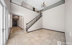 Corona apartment for rent - A spacious room with a staircase and a chandelier.