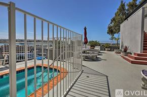 San Diego condo for rent - A pool surrounded by a metal fence with a red umbrella in the background.