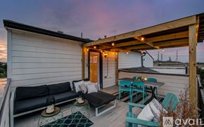 Houston townhouse for rent - A wooden deck with a black couch and a table with chairs.