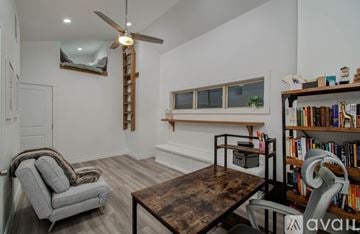 Houston townhouse for rent - A living room with a grey armchair, a wooden coffee table, and a bookshelf filled with books.