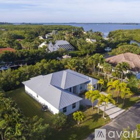 Vero Beach house for rent - A house with a white roof and a grey roof is surrounded by trees.