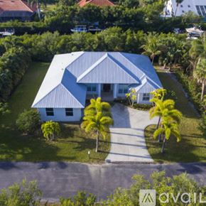 Vero Beach house for rent - A house with a blue roof and white walls surrounded by greenery.