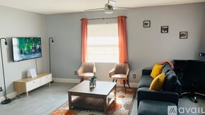 Ocala apartment for rent - A living room with a flat screen TV, a sofa, a chair, and a coffee table.