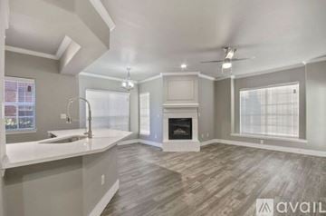 Fort Worth apartment for rent - A spacious living room with a fireplace and a kitchen area with a sink.