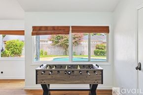 Dallas house for rent - A foosball table sits in a room with a window overlooking a pool.