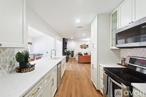 Dallas house for rent - A kitchen with white cabinets and a wooden floor.