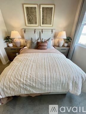 Sacramento apartment for rent - A bedroom with a bed, two nightstands with lamps, and a painting on the wall.
