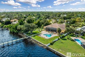 Port Charlotte house for rent - A house with a pool is surrounded by greenery and is located next to a body of water.
