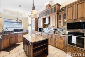 Port Charlotte house for rent - A kitchen with wooden cabinets and a granite countertop.