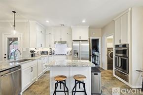 Lewisville house for rent - A kitchen with white cabinets and a marble countertop.