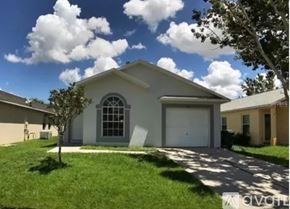 Winter Garden house for rent - A house with a white garage door and a tree in front.
