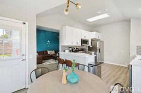 Saginaw house for rent - A modern kitchen with white cabinets and a dining table set with a vase and two chairs.