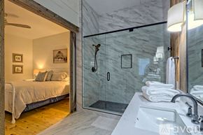 Clayton house for rent - A bathroom with a marble wall and a bedroom with a bed and a window.