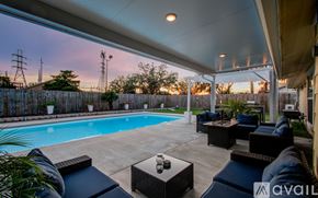 Houston house for rent - A pool surrounded by a patio with furniture and a fence.