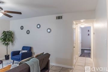 Gulfport apartment for rent - A living room with a blue chair, a couch, and a plant.