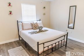 Gulfport apartment for rent - A bedroom with a neatly made bed and a mirror on the wall.