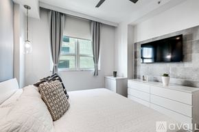 Miami apartment for rent - A modern bedroom with a large bed and a flat screen TV mounted on the wall.