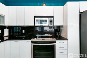 Miami apartment for rent - A kitchen with white cabinets and black countertops.
