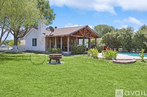 Mckinney house for rent - A house with a white exterior and a brown roof is surrounded by a green lawn and a pool.
